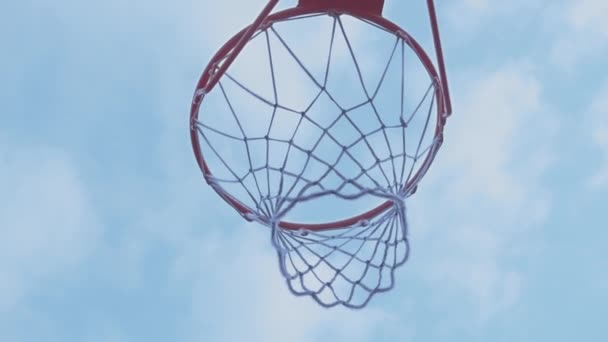 Баскетбольний м'яч проти блакитного неба з хмарами, в які м'яч потрапляє — стокове відео
