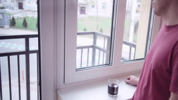 Człowiek z kubkiem kawy patrzy na ruch za oknem, kopiuje przestrzeń — Wideo stockowe
