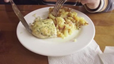 Tavuk pirzolası ve kızarmış patatesli tabak, bıçaklı ve çatallı adam, yakın plan.