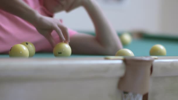 Bilardo masasında yatarken bilardo toplarıyla oynayan pembe tişörtlü genç adam. — Stok video