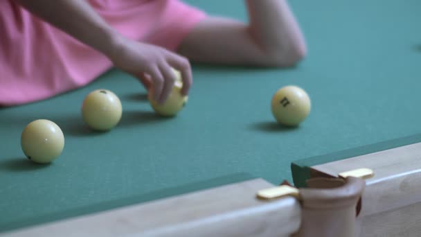 Hombre en una camiseta rosa acostado en una mesa de billar rueda bolas en un agujero de piscina — Vídeos de Stock