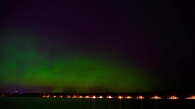 İsveç 'in kuzeyinde, gölün kenarında dans eden yeşil ve mor ışıkla birlikte 4K aurora borealis zamanı.