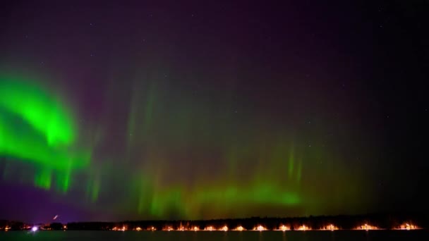 スウェーデン北部のオーロラの4Kタイムラプスで 街路灯のある湖の横で緑と紫の光を踊る — ストック動画