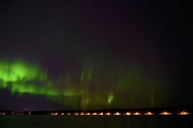 Aurora Borealis 'in manzara manzarası. Kuzey ışıklarının yeşil demeti. Yıldızlı gökyüzünün altında mor kuyruklu.