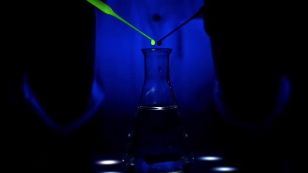 科学者は青い光の下で磁気攪拌機に赤と緑の色の溶液を混合している薬化学のための化学研究所で混合の旋回運動と — ストック動画