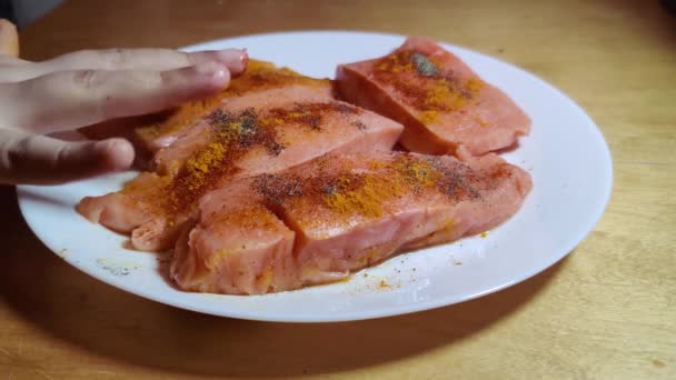 鮭の骨なしの赤魚は 油でパンを焼く前に白い皿の上に赤ちゃんの手でターメリック コショウでマリネされています — ストック動画