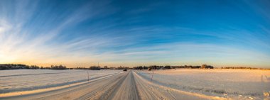 Kuzey ülkelerindeki turistik ziyaretler sırasında karla kaplı çam ağaçları ve açık mavi gökyüzü ile panoramik bir güneş ışığı ufku manzarası