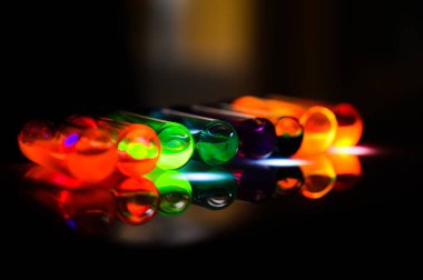 Bir kadın bilim adamının ultraviyole ışığı üzerinde yaptığı organik kimya laboratuarındaki çeşitli renkli cam kaplama şişesi.