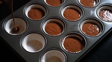 Çoklu metal kek tepsisine çikolatalı kek hamuru dökmek. Çikolatalı kek ya da muffin hamuru Bardak Kalıpları 4K video içine dökülüyor