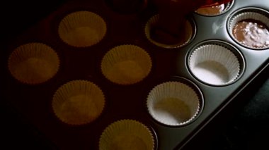 Çikolatalı kek hamurunu metal bir kek tepsisine döküyorum. Çikolatalı kek ya da muffin hamuru Bardak Kalıpları 4K video içine dökülüyor