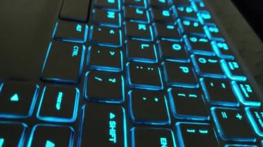 RGB ışıklandırmalı klavye sanal video oyunları için renk değiştiriyor ve karanlık ofis odasındaki güçlü bilgisayarda düzenleme yapıyor. Modern teknolojide gökkuşağı tayfı.