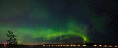 A multi colour Aurora borealis panorama on the starry night sky over a city. Aurora Borealis over Swedish lake Islands. Northern Sweden. Wintertime starry sky.