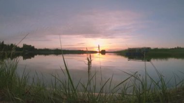 Gün batımı ve hareket eden bulutların altındaki turuncu gökyüzü ile birlikte büyüleyici panoramik göl manzarası. 2K yavaş çekim Kuzey Gölü manzarası. Güneş ufukta sakin bir manzarada batar.