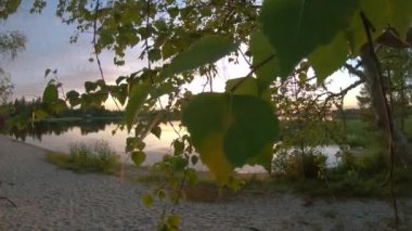 Gün batımı ve hareket eden bulutların altındaki turuncu gökyüzü ile birlikte büyüleyici panoramik göl manzarası. 2K yavaş çekim Kuzey Gölü manzarası. Güneş ufukta sakin bir manzarada batar.