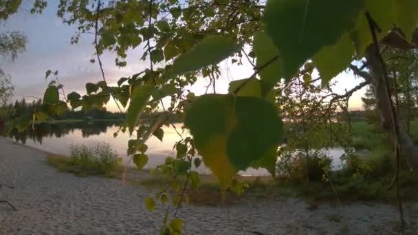 移動中の雲の下に夕日とオレンジの空と湖の地平線の素晴らしいパノラマビュー ノルディック湖の風景の2Kスローモーション 太陽が地平線上に沈む穏やかな風景 — ストック動画