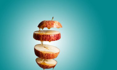 Taze dilimlenmiş kırmızı elma ve bal havada asılı duran yiyeceklere damlıyor. Alternatif şeker ikamesi, soğuk ilaç ve vücut güçlendirme, süper yiyecek kahvaltı rengi arka plan.