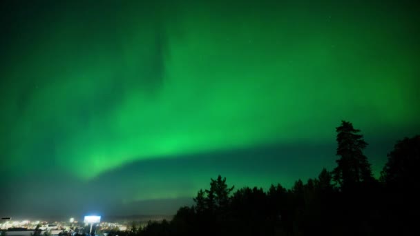 在瑞典北部 4K次的北极光带着绿光和紫光在一个有街灯的城市旁边舞动 — 图库视频影像