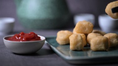 Kızarmış tavuk kanadı, tavuk nugget ve bir tabakta biftek kebabı. Kebap bir ketçap kasesine batırıldı. Masa üzerinde siyah bir arka plan 4K 'da bir Macro shot..