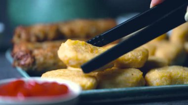 Kızarmış tavuk kanadı, tavuk nugget ve bir tabakta biftek kebabı. Kebap bir ketçap kasesine batırıldı. Masa üzerinde siyah bir arka plan 4K 'da bir Macro shot..