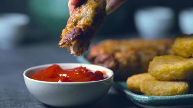 Kızarmış tavuk kanadı, tavuk nugget ve bir tabakta biftek kebabı. Kebap bir ketçap kasesine batırıldı. Masa üzerinde siyah bir arka plan 4K 'da bir Macro shot..