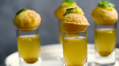 Baharatlı suyla kaplı bir bardakta Hint sokak yemeği fuşkası yakın. Pani puri Hindistan 'da bir sohbet konusu. 4K Hint sokak yemekleri.