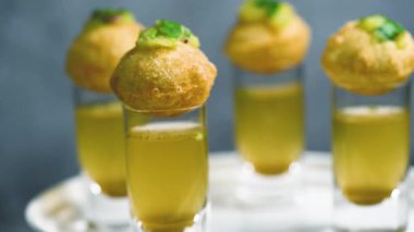 Baharatlı suyla kaplı bir bardakta Hint sokak yemeği fuşkası yakın. Pani puri Hindistan 'da bir sohbet konusu. 4K Hint sokak yemekleri.