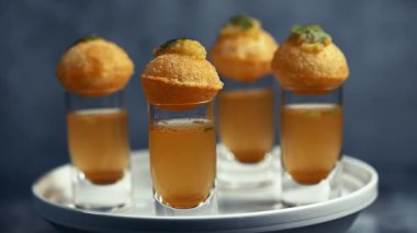 Baharatlı suyla kaplı bir bardakta Hint sokak yemeği fuşkası yakın. Pani puri Hindistan 'da bir sohbet konusu. 4K Hint sokak yemekleri.