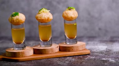 Baharatlı suyla kaplı bir bardakta Hint sokak yemeği fuşkası yakın. Pani puri Hindistan 'da bir sohbet konusu. 4K Hint sokak yemekleri.