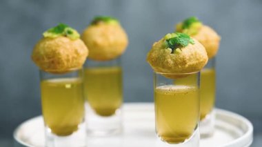 Baharatlı suyla kaplı bir bardakta Hint sokak yemeği fuşkası yakın. Pani puri Hindistan 'da bir sohbet konusu. 4K Hint sokak yemekleri.