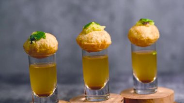 Baharatlı suyla kaplı bir bardakta Hint sokak yemeği fuşkası yakın. Pani puri Hindistan 'da bir sohbet konusu. 4K Hint sokak yemekleri.