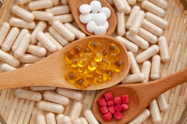 Sağlıklı yaşam tarzı, vitaminler, mineraller ve örülmüş bambu bir tabağın içindeki tahta kaşıklardaki besin takviyeleri. Üst Manzara. Yakın plan..