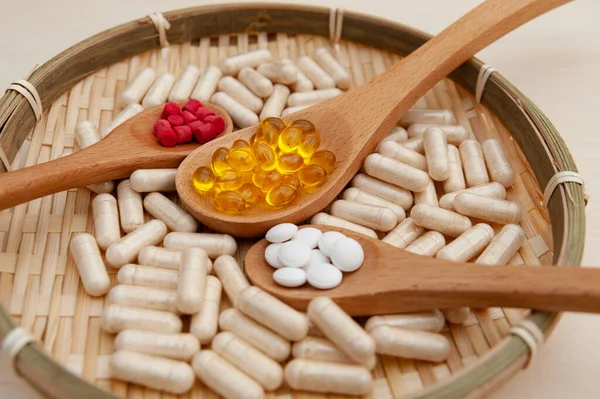 Sağlıklı yaşam tarzı, vitaminler, mineraller ve örülmüş bambu bir tabağın içindeki tahta kaşıklardaki besin takviyeleri. Yakın plan..