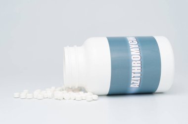 AZITROMYCIN antibiyotiği beyaz şişe ambalajında dağınık haplarla birlikte. COVID-19 tedavisi. Beyaz arka planda izole edilmiş. Uzayı kopyala Yakın plan..