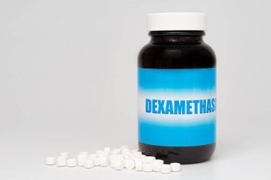 DEXAMETHASone cam şişe ambalajı dağınık haplarla. COVID-19 tedavisi. Beyaz arka planda izole edilmiş. Uzayı kopyala Yakın plan. Yatay çekim.
