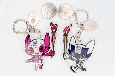 Tokyo, Japonya - 4 Ocak 2021: Tokyo 2020 Olimpiyatları için maskot anahtarlıkları ve 100 yenlik hatıra paraları.