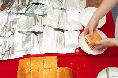 Brezilya Portekizcesinde BOLO GELADO adı verilen geleneksel Brezilya pastası. Adım adım: Kadınlar pastayı süte bandırıyor. Üst Manzara. Yatay çekim.