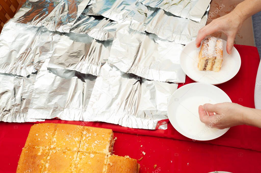 Traditional Brazilian cake called BOLO GELADO in Brazilian Portuguese - Making step by step: Womans hand putting cake in grated coconut. Top view.