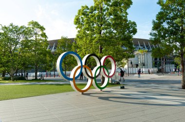 Shinjuku City, Tokyo, Japan - June 12, 2021: Olympic Rings in front of New National Stadium also called Tokyo Olympic Stadium. Beautiful blue sky background. clipart