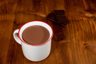 Bir fincan sıcak çikolata ve koyu beton arka planda çikolata parçaları.