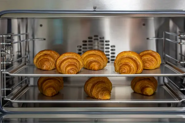 Baking tray with delicious croissants in oven