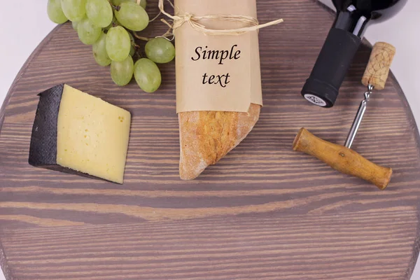 Corkscrew, wine, baguette, grape and hard cheese on an old wine barrel texture close up.Food still life on beautiful cutting board with copy space for text. — Stock Photo, Image