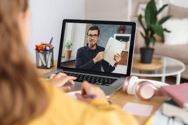 Uzaktan öğrenme. Öğrenciyle online matematik dersi alan erkek öğretmen, web kamerası kullanarak görevi açıklıyor. Evden uzakta ders çalışan, özel öğretmenden ders alan bir kız. Karantina sırasında evde eğitim