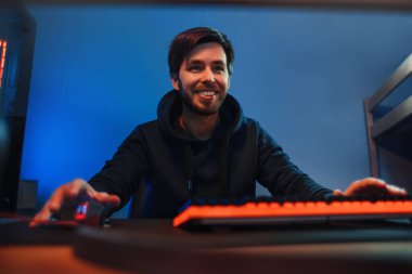 Genç profesyonel oyuncunun portresi eğleniyor, geceleri evde oyun oynuyor, video üzerinden oyun oynuyor. Adam arkadaşlarıyla çok oyunculu oyun oynuyor. Ön manzara, oda arkaplanı, neon rengi