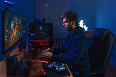 Concentrated Pro Gamer Playing Game, Taking Part In Online Tournament Sitting At Computer At Home. Low Light, Neon Color, Side-View. Professional cybersport player training online game on his PC clipart