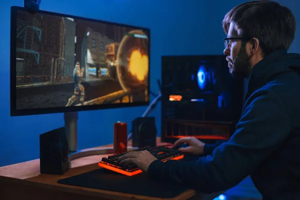 Online Cyber Sport Game 'de oynayan genç beyaz profesyonel oyuncu evinde, modern bilgisayardaki odasında. Siber sporcu adam takımıyla turnuvalara katılıyor. Yan görüş. Bilgisayar bağımlılığı kavramı