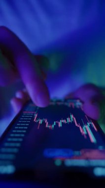 Kripto işlemcisine yakın plan mavi ve mor neon ışık altında yatırım şemasını kontrol et, finans piyasalarını, hisse senetlerini ve kripto para birimlerini analiz et. Dikey video