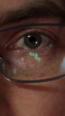 Gözlüklerine yansıyan şamdan grafikleri ve finansal grafikleri olan bir kripto tüccarı ya da yatırımcı gözünün yakın çekimi. Kripto para birimi ya da borsa konsepti. Dikey video