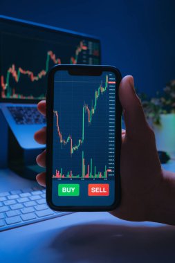 Şifreli döviz veya borsa uygulaması olan, çevrimiçi ticaret, finans teknolojisi ve dijital yatırımları temsil eden, tüccarların el ele tutuşan telefonlarına yakın plan. 