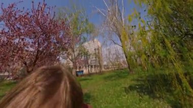 POV manzarası, babasının neşeli oğlunu bir parkta havaya fırlatması, gülen çocuğun kollarını geniş açması, güneşli bir yaz gününde babasıyla dışarıda eğlenmesi. Aile eğlencesi