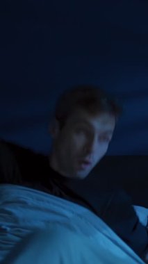 Şok olmuş bir adam gece aniden uyanır ve yatakta oturur, hızlı bir şekilde ürker ve nefes alır çünkü kâbus zaten sorunlu olan uykusunu bozar. Uyku bozukluğu, uykusuzluk ve gece terörü. Dikey video